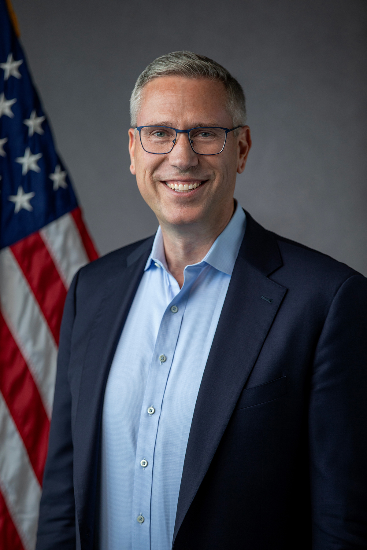 Head-and-shoulders portrait of an elected official in a blue shirt with his arms crossed