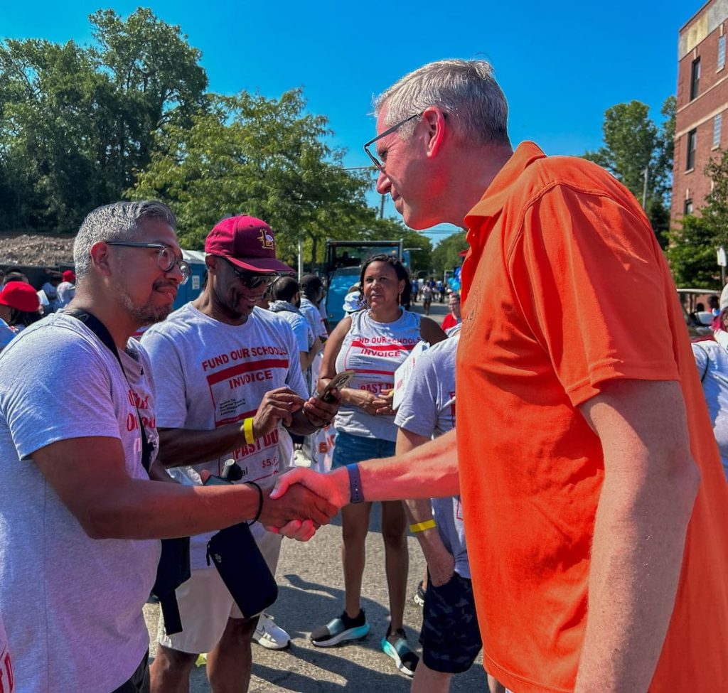 men shaking hands at a festival smiling