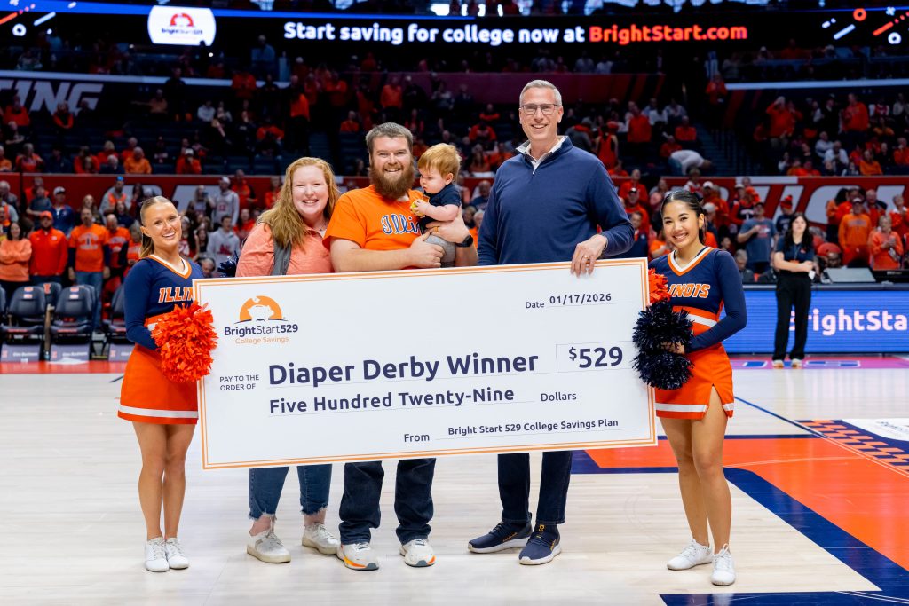 group of people holding a giant check on the court at a college basketball game 