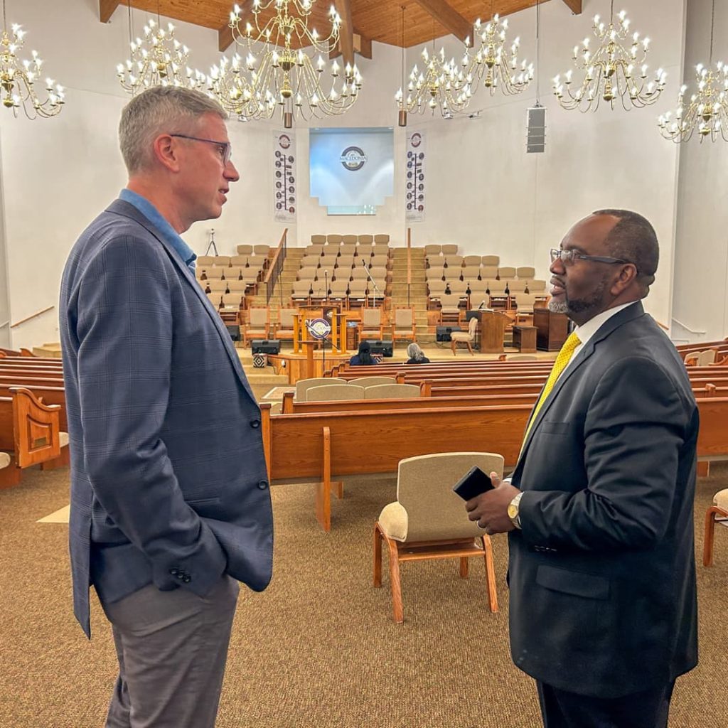 two men speaking to each other in an empty church