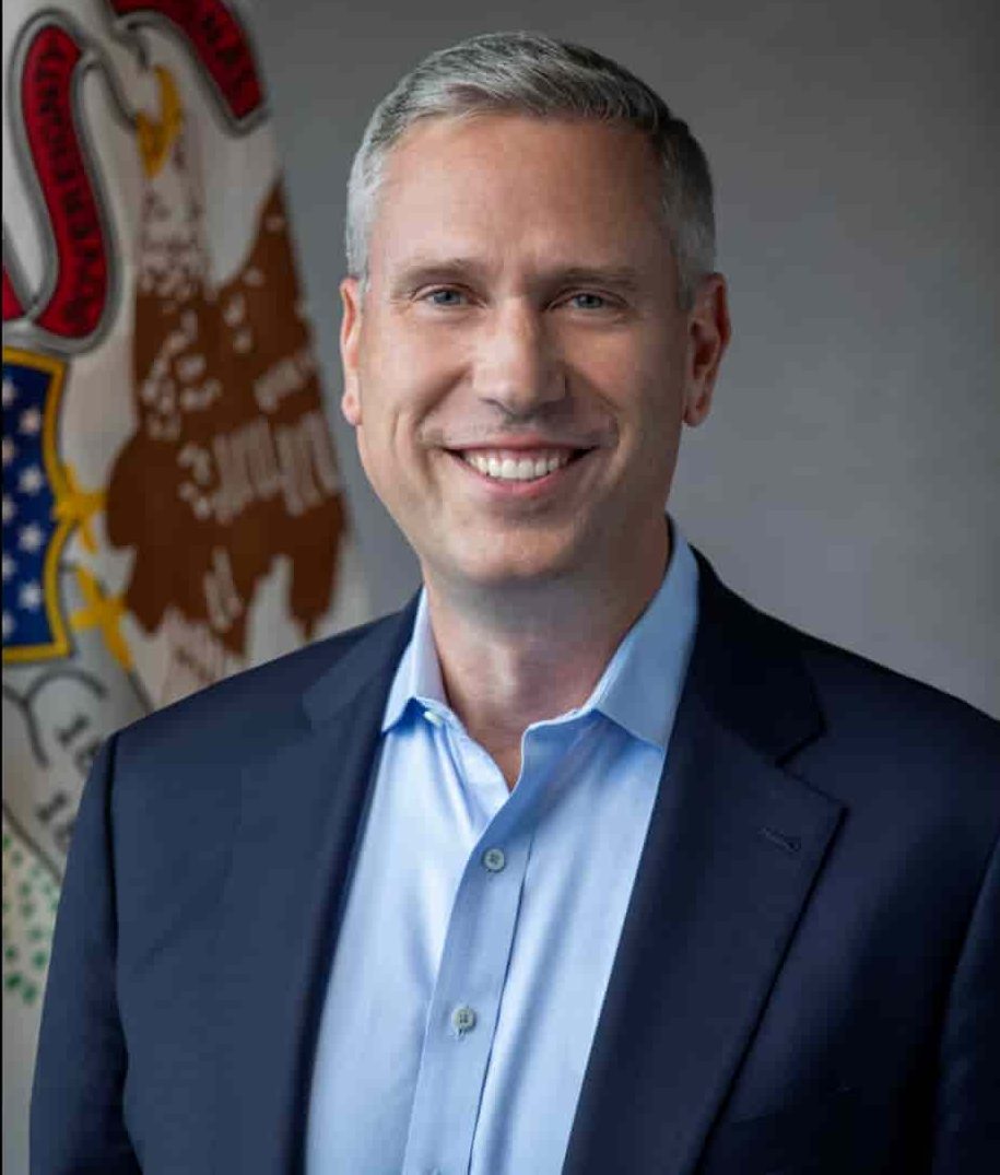 man smiling at camera with Illinois flag in the background