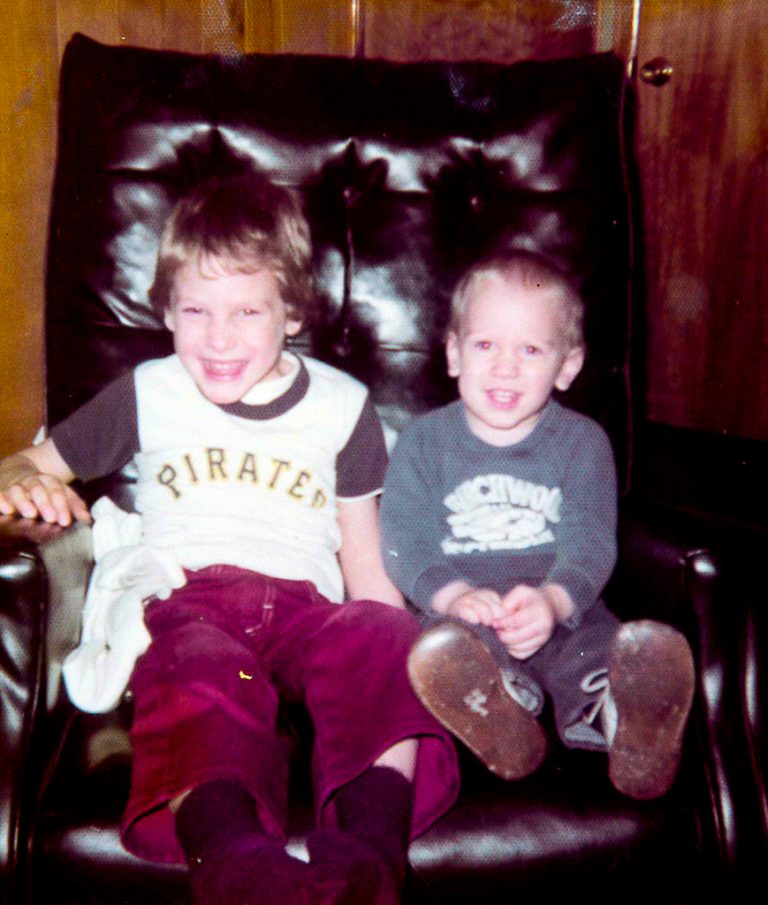 Two young boys sitting in an easy chair and smiling