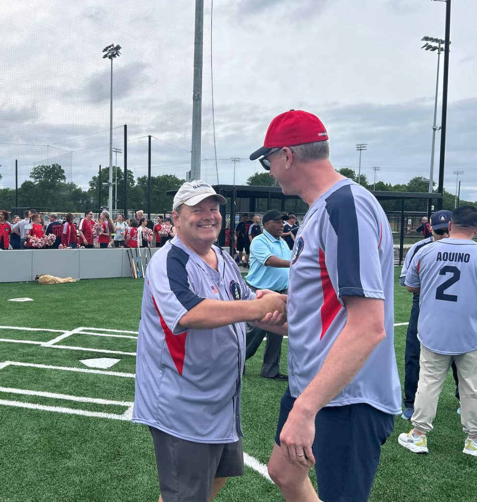 two men on a softball field shaking hands